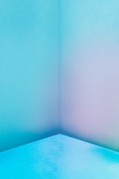 the corner of a room with blue walls and a teddy bear sitting on top of it