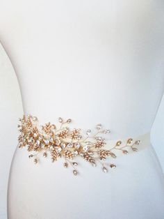 a bridal belt with pearls and leaves on it's side, attached to a mannequin torso