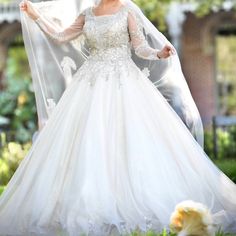 a woman in a white wedding dress holding a veil over her head and posing for the camera