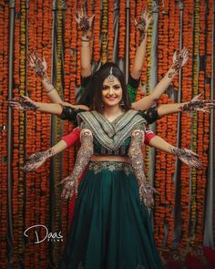 a woman in a green and red outfit with her arms spread out, surrounded by orange flowers