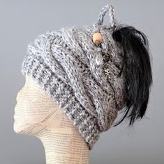 a knitted hat on top of a mannequin's head with buttons