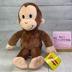 a brown stuffed monkey sitting next to a small book