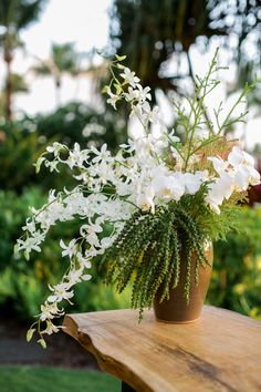 a vase with white flowers on a wooden table in a garden or park area,