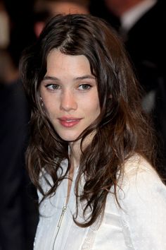 a close up of a person wearing a white shirt and black pants with long hair