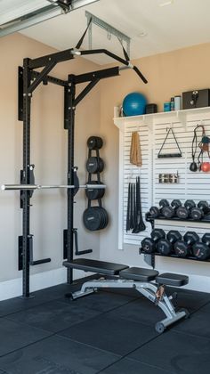 a home gym with black flooring and lots of exercise equipment on the wall behind it