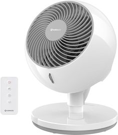 a white fan sitting on top of a table next to a remote control and an air vent