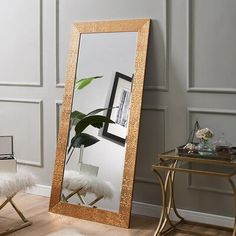 a large mirror sitting on top of a wooden floor next to a chair and table