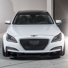 the front end of a white car parked in a garage