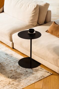 a black table sitting on top of a wooden floor next to a white couch in a living room