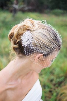 a woman in a wedding dress with a veil on her head is looking down at the ground