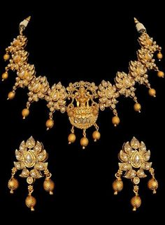 Traditional Indian temple bridal jewelry with stunning pearl stone-setting on a gold plated necklace & earrings. This temple choker jewelry set is elaborated with a goddess motif design pendant, making it one of a kind. Gold plated choker necklace with goddess engraved & floral design adorn this bridal neckpiece.  Stunning golden ball drops on this jewelry set is sure to make you feel like a million bucks with their elaborating handcrafted design. This short necklace set comes along with a beaut Elegant Chandbali Bridal Sets For Puja, Elegant Bridal Sets For Puja Festivals, Elegant Kundan Necklace With Peacock Design For Puja, Elegant Hand Set Temple Necklace For Puja, Gold Jewelry Sets With Peacock Design For Festivals, Gold Chandbali Pearl Necklace For Puja, Gold Kundan Jewelry For Spiritual Occasions, Gold Plated Temple Jewelry Sets, Elegant Bridal Necklace With Peacock Design For Puja