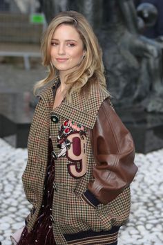 a woman is walking down the street with a handbag on her shoulder and wearing a plaid jacket