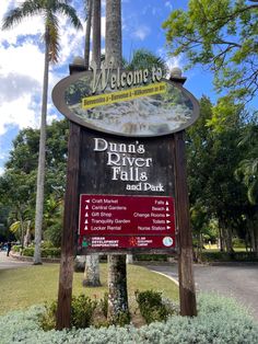 a sign for dunin's river falls and park with palm trees in the background