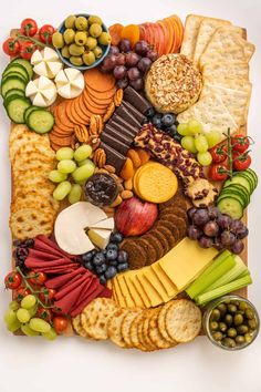 a platter filled with cheese, crackers, grapes, and other food items