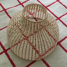 a woven basket sitting on top of a white and red rug in the middle of a room