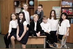 a group of young children sitting on top of a wooden desk in front of bookshelves