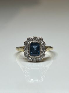 a blue and white diamond ring sitting on top of a table