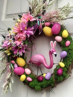 a pink flamingo wreath with easter eggs, flowers and grass on the front door