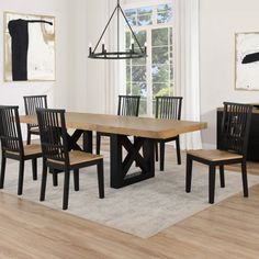 a dining room table with four chairs and a rug on the floor in front of it