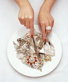 a woman is holding a plate with jewelry on it and her hands are touching the plate