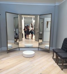 two women are walking through an open door in a room with mirrors on the wall