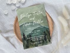 the wedding card is sitting on top of a plate next to some flowers and feathers