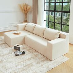 a white couch sitting on top of a hard wood floor next to a large window