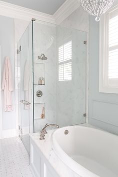 a bathroom with a large tub and walk in shower next to a white tiled floor