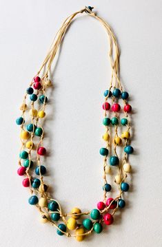 multicolored beaded necklace on a white surface with beads hanging from it's sides