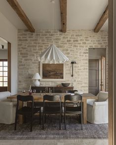 a dining room table with chairs and an umbrella hanging from it's ceiling in front of a brick wall