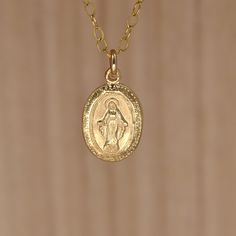 "Gold Virgin Mary Pendant Necklace. Miraculous Medal Necklace. A Miraculous Medal necklace in all 14K gold filled materials. The tiny pendant is understated and lightweight, yet sturdy. It measures approximately 12X9mm  (about 1/2 inch X 5/16 inch). It shows an image of the Virgin Mary crowned with a halo. The tiny letters around the circumference of the pendant read: \"O Mary conceived without sin pray for us who have recourse to Thee. \" What is gold-filled? Gold-filled jewelry contains almost 100 times more gold than gold-plated jewelry. Get the look and quality of karat gold at a fraction of the price.Find similar items in my shop: Browse my shop: ALLDANAE.etsy.com" Gold Charm Necklaces With Round Pendant, Gold Charm Necklace With Round Pendant, Dainty Miraculous Medal Charm Necklace As Gift, Dainty Miraculous Medal Charm Necklaces As Gifts, Dainty Charm Necklaces With Miraculous Medal For Gifts, Dainty Charm Necklaces With Miraculous Medal As Gift, Tiny Gold-plated Charm Necklaces, Tiny Gold Plated Charm Necklaces, Tiny Gold Pendant Necklace