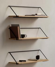 two shelves with books, coffee cup and notebooks on them against a white wall