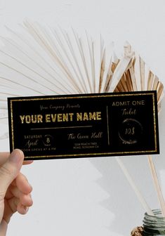 a person holding up a black and gold event ticket