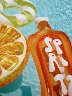 an inflatable slice of orange sitting on the side of a swimming pool next to another float