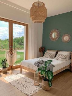 a bed room with a neatly made bed next to a large window and a potted plant