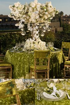 the table is set with white flowers and green linens