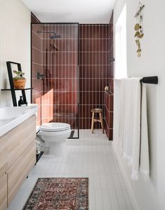 a white toilet sitting in a bathroom next to a walk in shower and wooden cabinets