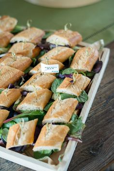 a platter filled with sandwiches on top of a wooden table