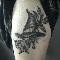 a black and white photo of a witch's hat with flowers on the thigh