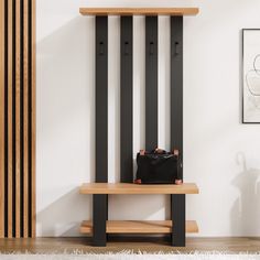 a black purse sitting on top of a wooden bench in front of a white wall