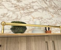 a kitchen shelf with dishes and cups on it, next to a marble counter top