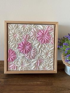 a wooden frame with pink and white flowers on it next to a potted plant