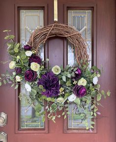 a wreath with purple and white flowers hangs on the front door