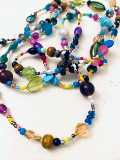 "This is a fun, super colorful, boho style beaded necklace. I made it with an assortment of stone, glass, plastic and metal bead, seed beads, pearls and more! Wear it long or wrap it! Length: 54\"; has no clasp.    Thank you so very much for visiting my shop!!  Click here for more: http://www.etsy.com/shop/jHenSunshine  New to my shop? See my policies section for any additional questions." Adjustable Multicolor Crystal Necklaces With Large Beads, Adjustable Multicolor Crystal Necklace With Large Beads, Bohemian Czech Glass Tiny Beads, Bohemian Oval Czech Glass Beads, Bohemian Czech Glass Oval Beads, Colorful Oval Beaded Jewelry For Festivals, Multicolor Beaded Chain Necklace With Metal Beads, Bohemian Turquoise Beaded Bracelets With Dangling Beads, Unique Long Beaded Necklace With Faceted Beads