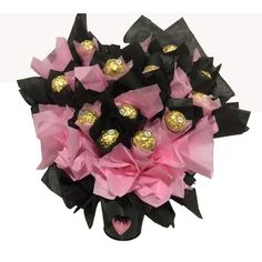 a bouquet of chocolates wrapped in black and pink tissue paper with gold foil hearts