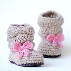 a pair of crocheted baby boots with pink bows