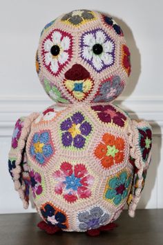 a crocheted stuffed animal sitting on top of a wooden table next to a wall