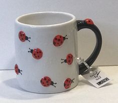 a coffee mug with ladybugs on it is sitting on a white counter top