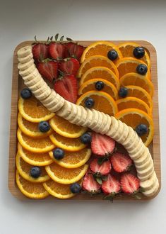 sliced bananas, oranges and strawberries on a cutting board