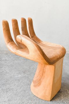 a wooden sculpture of a hand holding something in it's palm like position on the ground